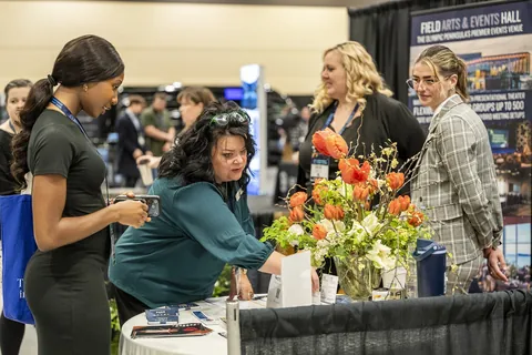 Exhibitors and attendees talking beside a floral display at Northwest Event Show.